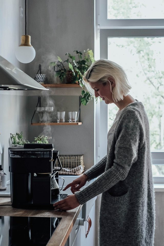 Blonde woman standing in front of the kitchenette with the first electrical Pour Over system by Melitta®.